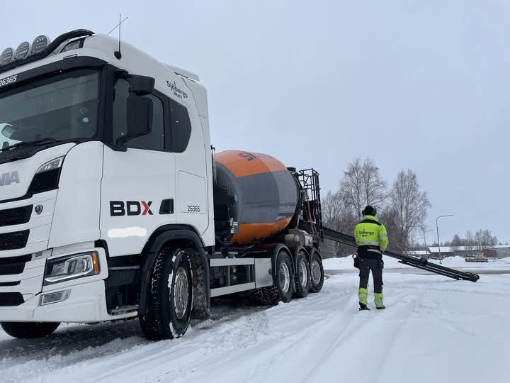 Chaufför från Sjöbergs Åkeri gör i ordning rännan på en betongbil vintertid